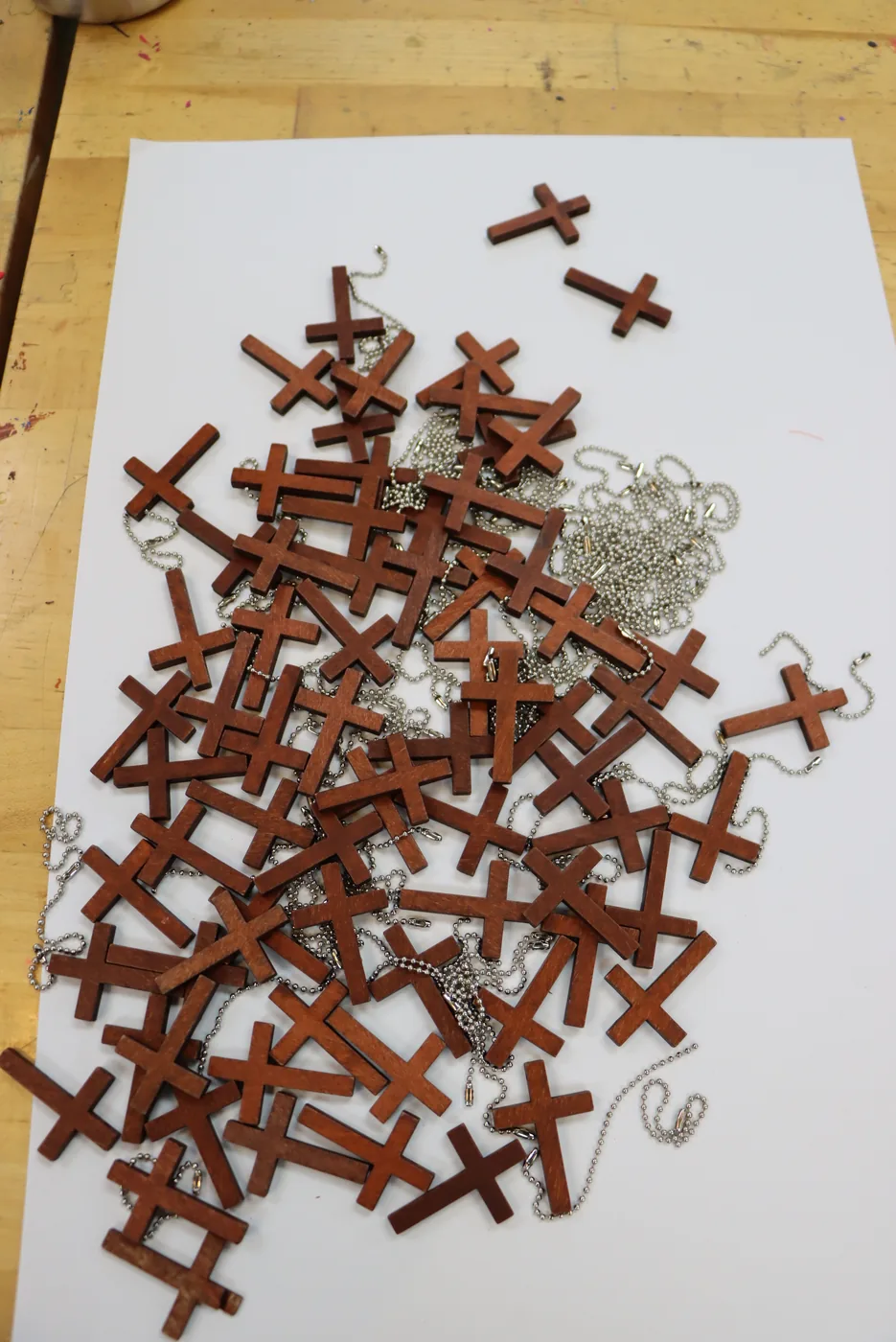 Wooden cross necklaces spread across a craft table