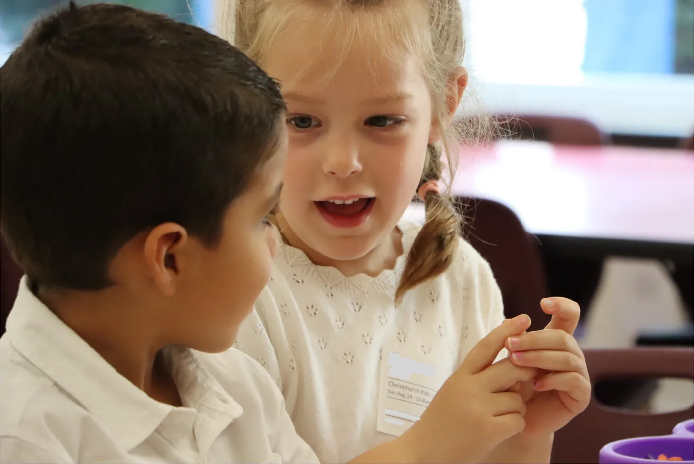 Two children leaning in close together at a Christchurch Kids table