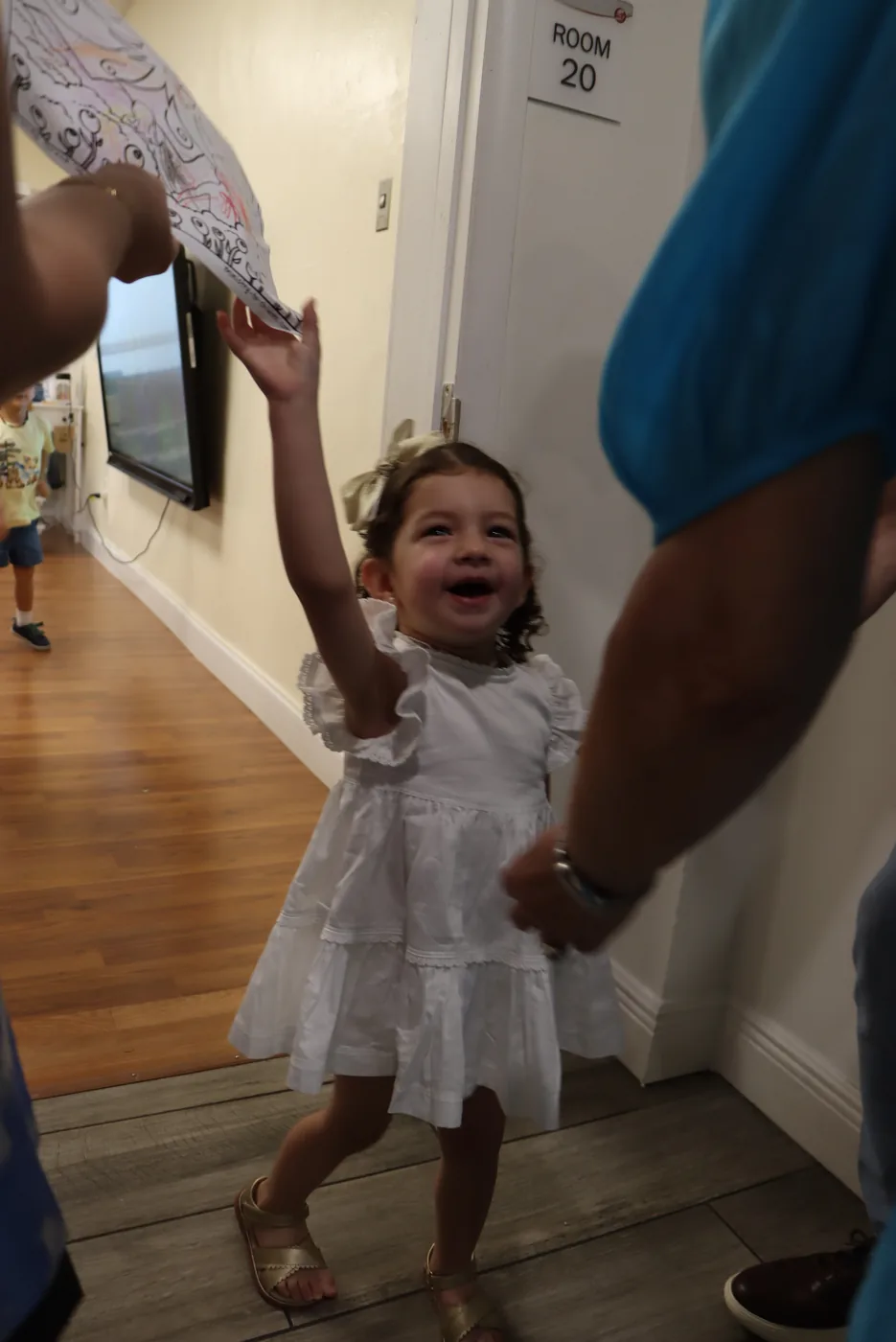 A toddler laughing as she reaches up for her drawing