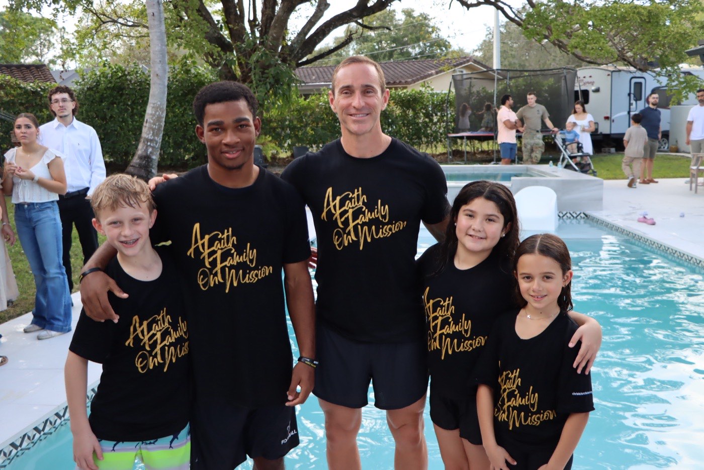 Five members of Christchurch Miami at a poolside, wearing shirts reading A Faith Family On Mission