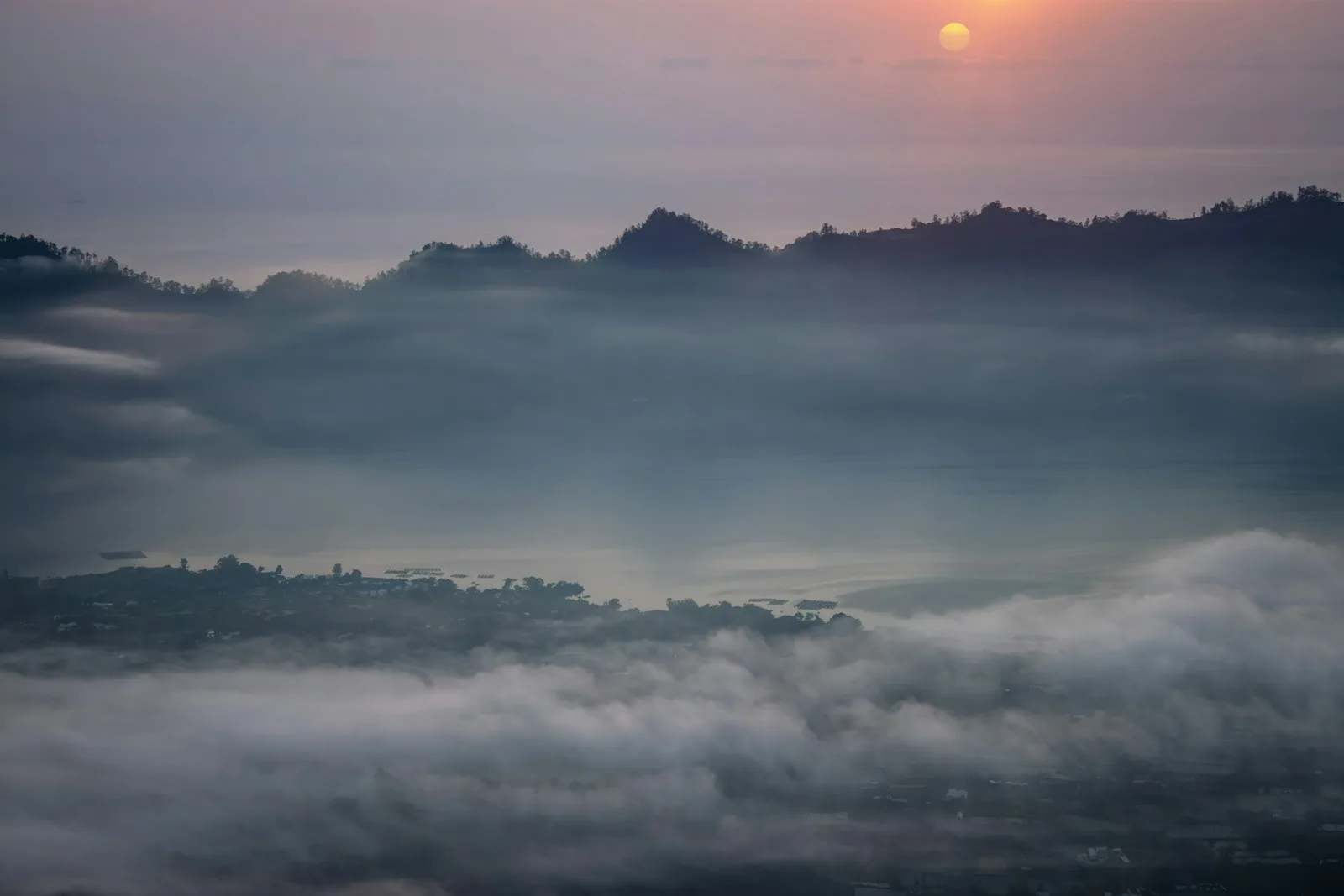 Misty mountains at sunrise under soft light.