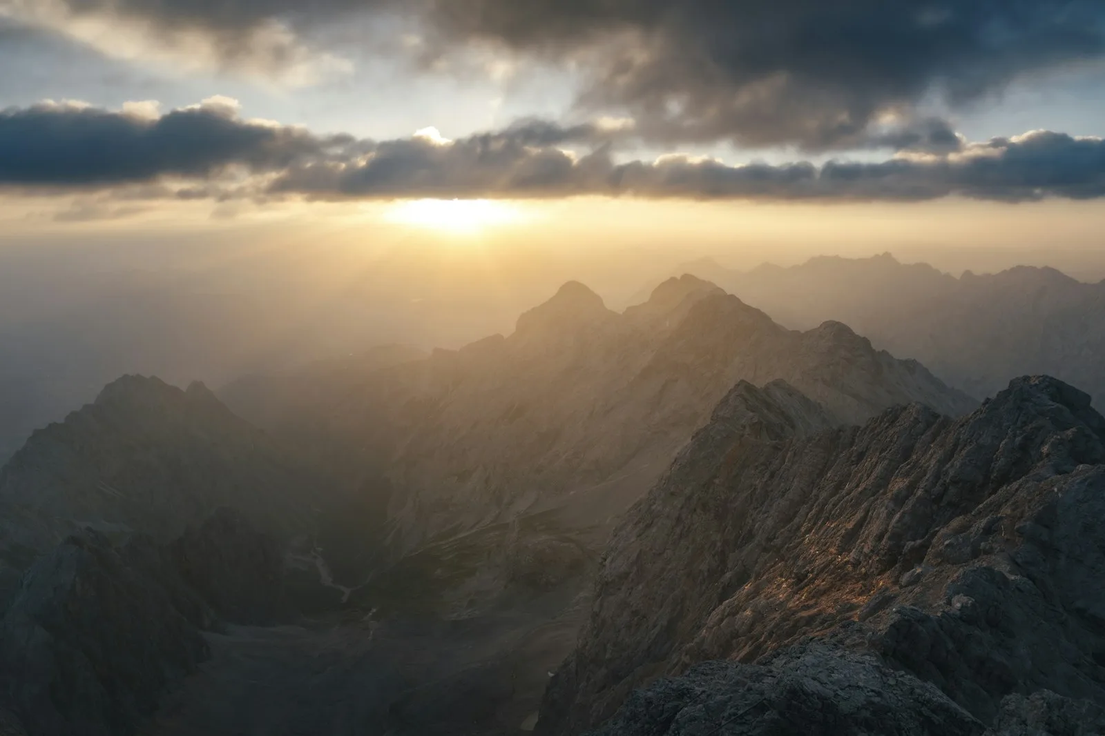 Sunbeams breaking through clouds over distant mountain peaks.